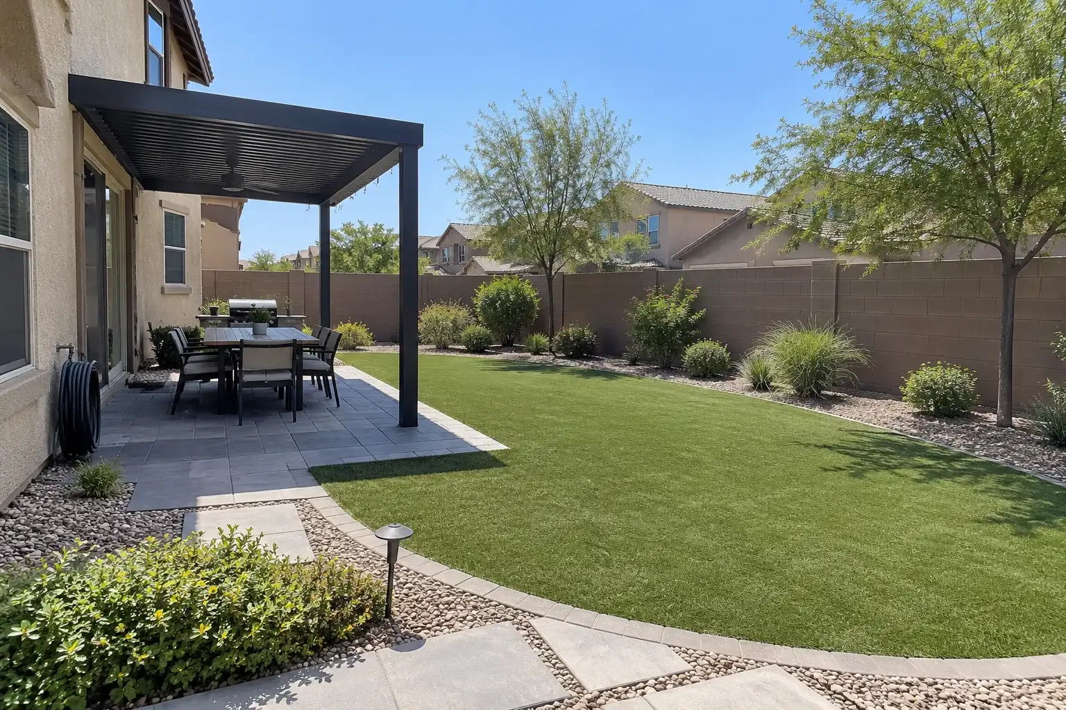 Family backyard with a curved artificial turf lawn, a paver walk and a dark metal pergola over a dining table